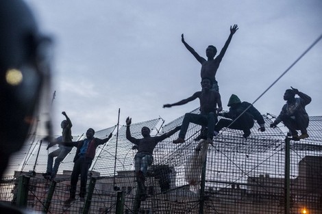 Would-be immigrants react on a fence near Beni Enza, into the north African Spanish enclave of Melilla on March 28, 2014. Several hundreds people launched a dawn assault today to cross into the Spanish city, which lies on the northern tip of Morocco, and dozen made it across. AFP PHOTO/ JOSE COLON